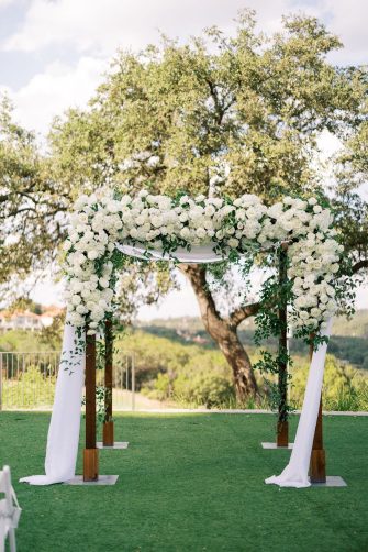 Traditional chuppah at outdoor ceremony with all white flowers.